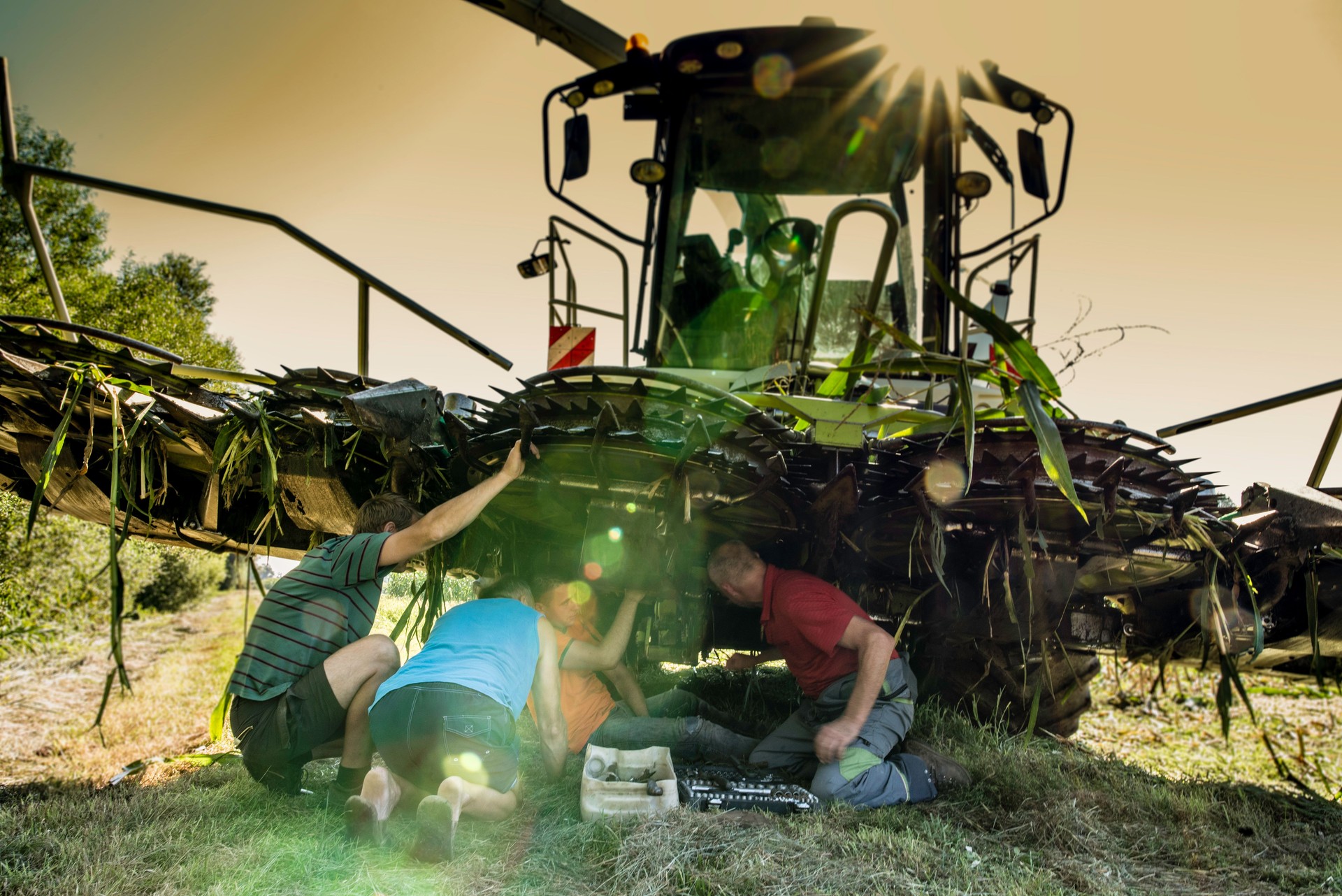 Men examining combine harvester malfunction